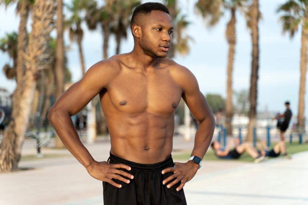 Summer portrait of african american muscular man with naked torso standing at the sun while relaxing after sport